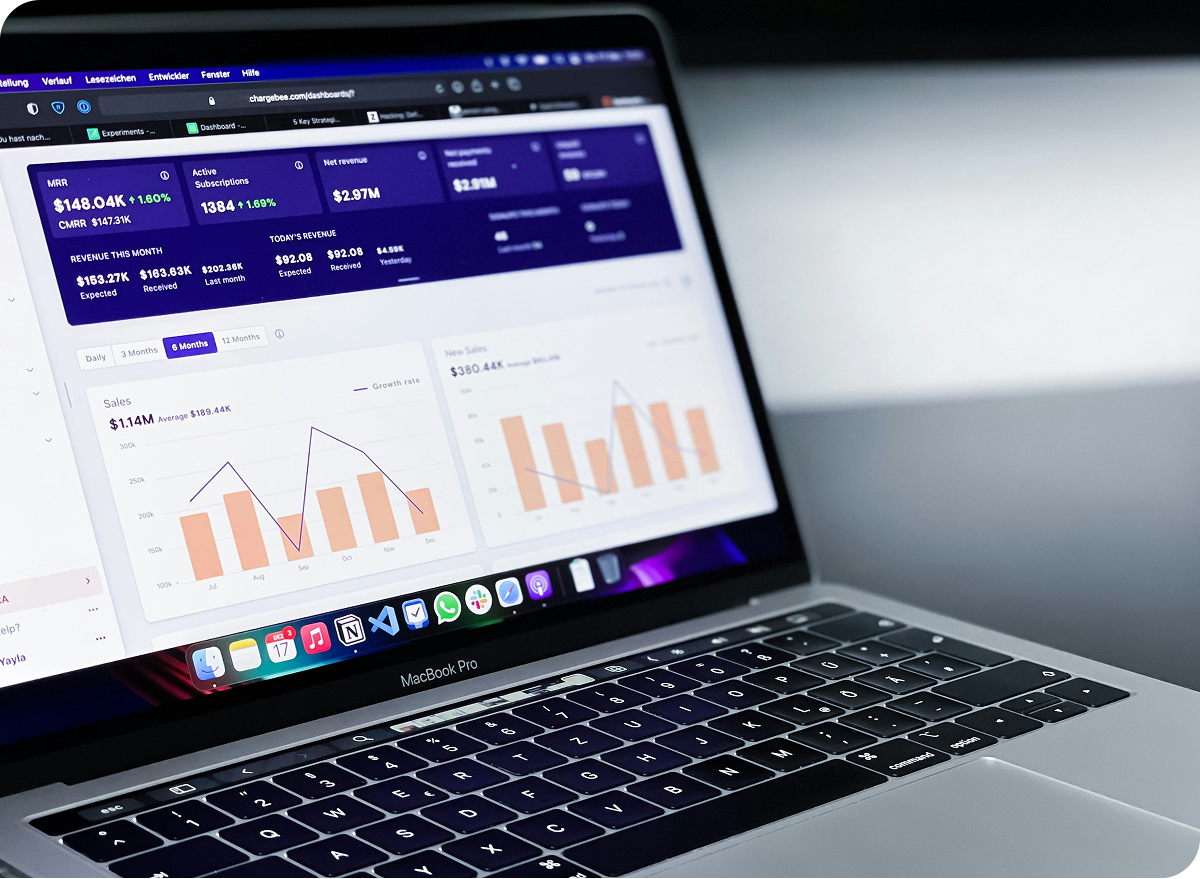 グラフや数値データが並ぶ管理画面を映したノートPCで、業績やKPIを分析している様子を示す画像